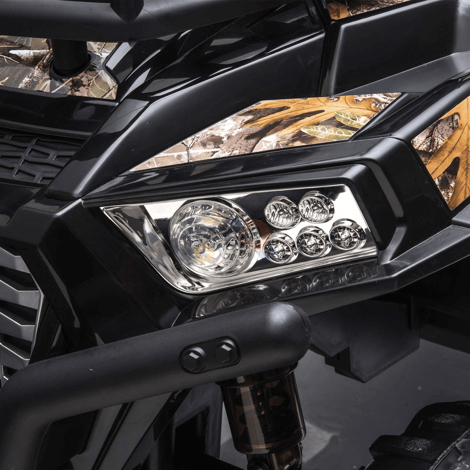 Close-up of the Camo 2 Seats Golf Buggy 24V Editions headlight, showcasing round light elements against camo bodywork. Its angular lines and black trim enhance the rugged, adventurous design of this kids ride-on car.