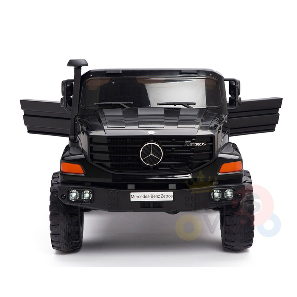 Front view of a Black 24V XXL Mercedes-Benz Zetros Kids Ride On Truck with its doors open. This 2-seater features large tires, detailed headlights, and a prominent grille showcasing the Mercedes-Benz emblem. The background is plain white.