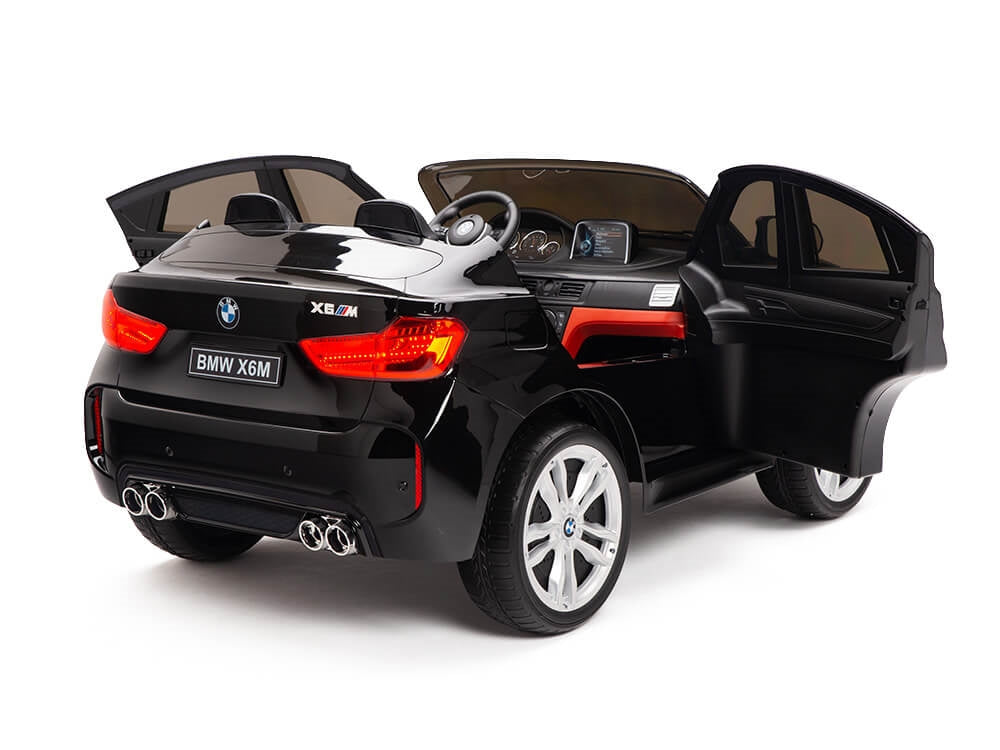 The Black 12V Licensed XXL BMW X6 Ride On Car offers kids a stylish ride with open doors, detailed interior, dual exhaust, and silver wheels. Featuring seating for two, it includes a steering wheel and dashboard for an authentic driving experience.