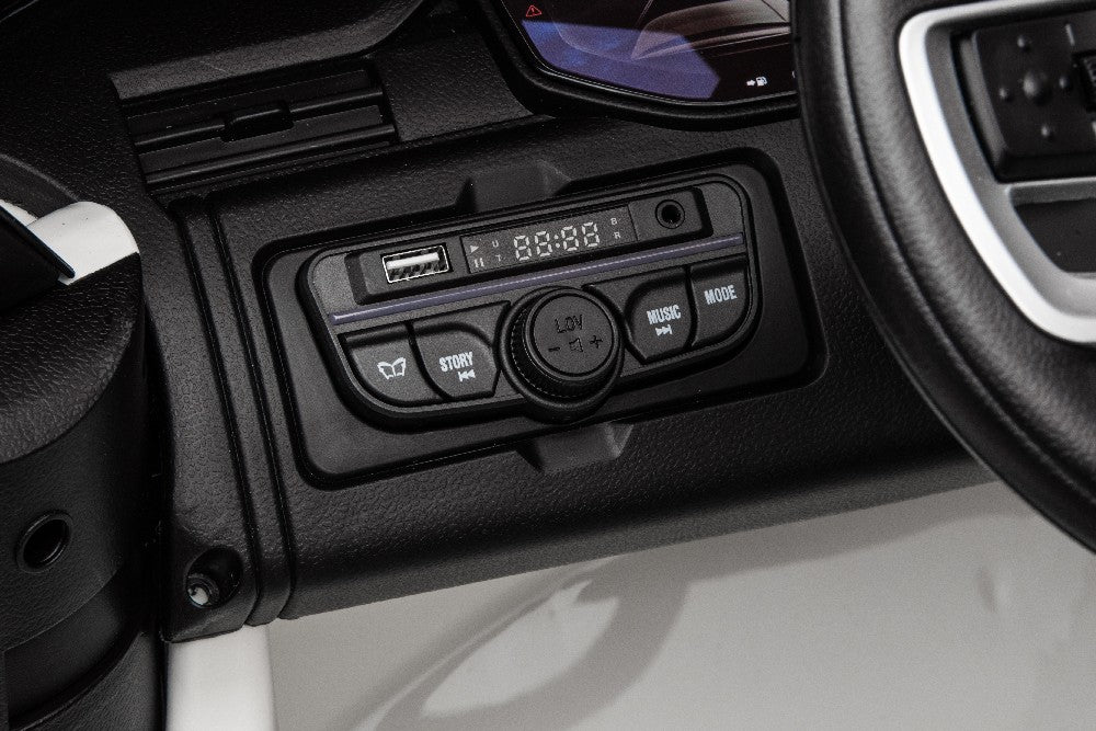 Close-up of a Black 24V Kids Range Rover dashboard showcasing a media control panel with USB, story, music, and mode selection buttons. A central digital display is visible. On the right side, part of the steering wheel can be seen, emulating controls in the Luxury Ride-On SUV.