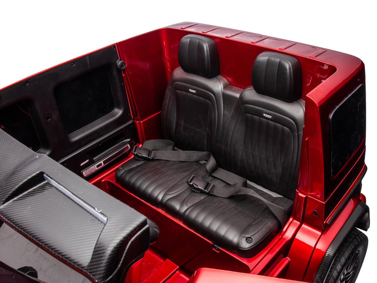 The Red Metallic 2x24V/4WD Platinum XXL Mercedes G63 Ride-On Truck features two black leather seats with seatbelts, glossy red panels, EVA wheels, and MP4 functionality. Remote control access enhances its stylish design and functionality.