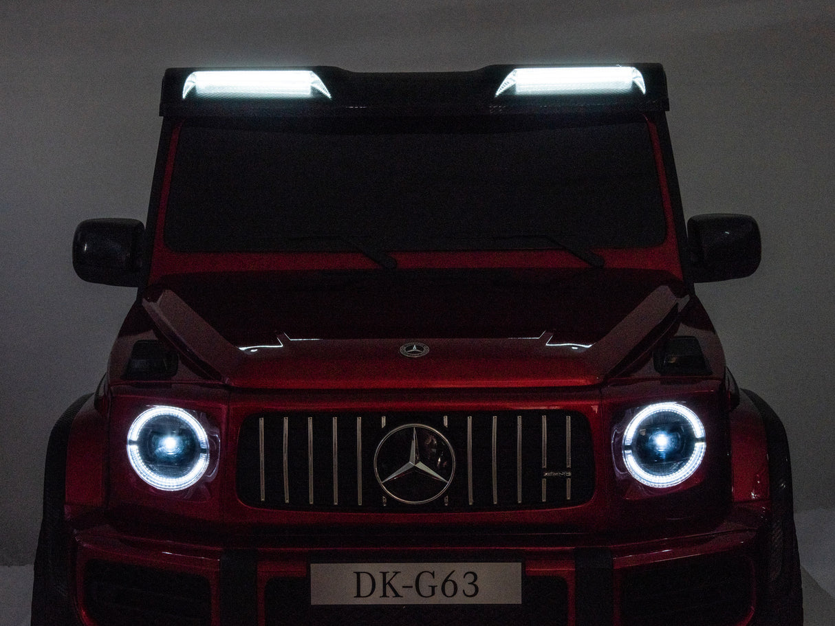 A Red Metallic 2x24V/4WD Platinum XXL Mercedes G63 Ride-On Truck with MP4 is shown from the front, featuring illuminated headlights, roof lights, EVA Wheels, leather seats, remote control access and a DK-G63 license plate.