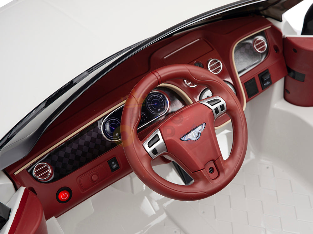 Close-up of a luxury cars dashboard featuring a red leather-wrapped steering wheel with metallic accents and sleek interior, reminiscent of the White 12V Bentley GTC Kids Licensed Ride On Car with Rubber Wheels, Remote, including round air vents, digital display with circular gauges, and wood trim.