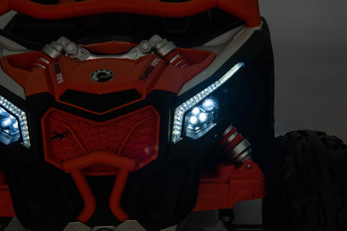 Close-up of the Orange 2x24V/4WD Official Can-Am Maverick Ride on Buggy, LX Performance’s rugged front section with distinct LED headlights and bold angular design. The primarily black and orange vehicle features visible shock absorbers, Eco Leather Seats interior, and a textured grille for off-road adventures.