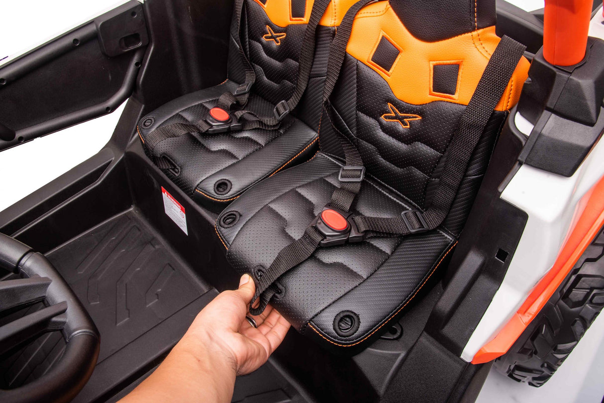 A person buckles the seatbelt on an Orange 2x24V/4WD Official Can-Am Maverick Ride-on Buggy, LX Performance. The mini car features sporty black eco leather seats with orange accents and reveals a steering wheel and tire, hinting at adventure.