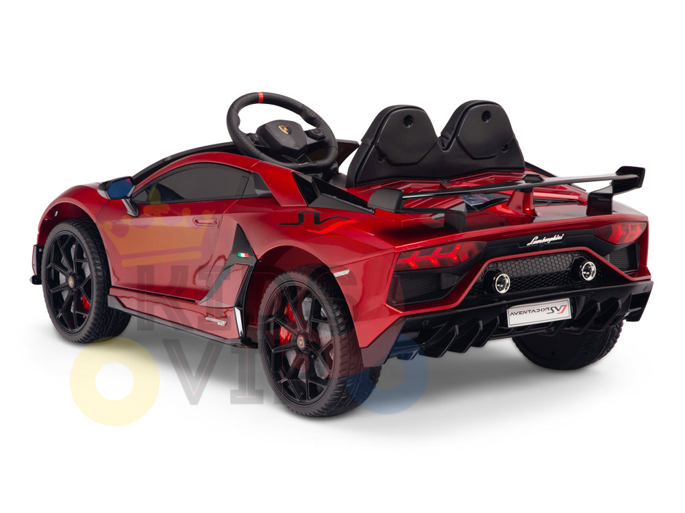 The Burgundy Red 12V Lamborghini SVJ Sport Kids Licensed 1 Seater Ride On Car features a sleek sports-like design with black seats, rubber wheels, steering wheel, and rear spoiler. It operates on a 12V battery and includes a remote. Presented against a white backdrop to highlight its shiny finish.