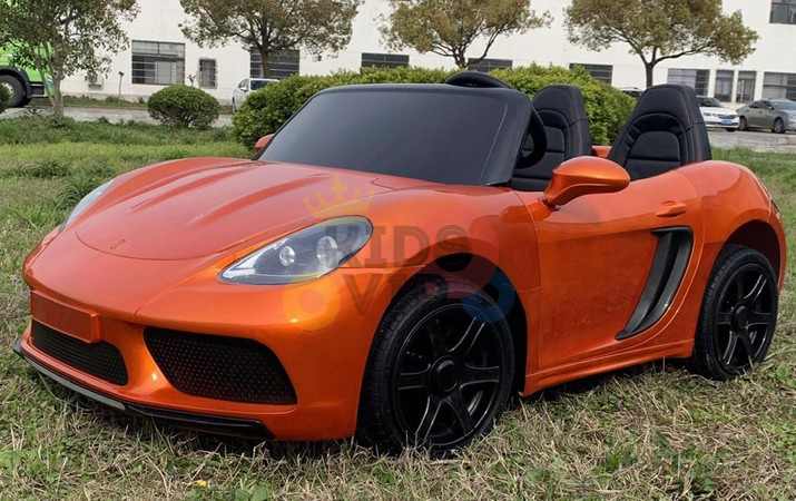 The Orange 24V XXL SuperSport Big Kids Ride On Car is a small orange convertible with a powerful 180W brushless motor, black wheels, real tires, and two seats for an authentic sports car experience on grass.
