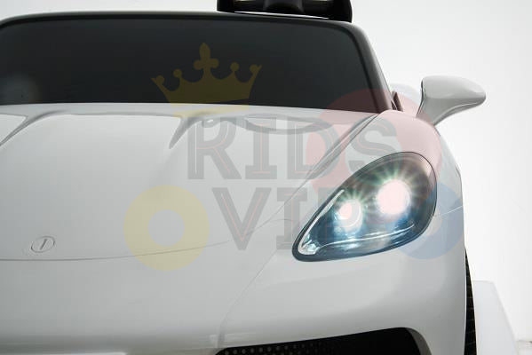 Close-up of a sleek White 24V XXL SuperSport Ride On Car, highlighting the front left headlight. It features a glossy finish, modern design, and tinted windshield. Semi-transparent text and colorful circles overlay the image for a playful twist on its elegance.
