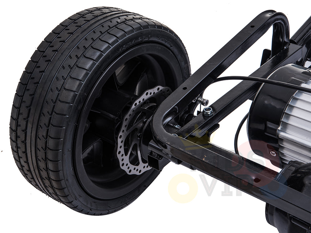 A close-up of a black wheel is attached to a metal frame featuring a visible brake disc and tire tread, housing industrial components with an 180W brushless motor, indicative of its use in the Metallic Blue 24V XXL SuperSport Big Kids Ride On Car.