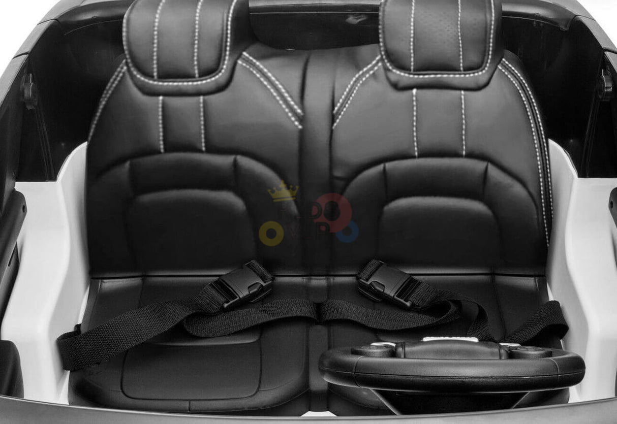 The Pink 24V Official Range Rover Complete MP4 Edition Kids Ride On Car features two black faux leather seats with white stitching, each equipped with a black seatbelt, and a small steering wheel positioned in front.