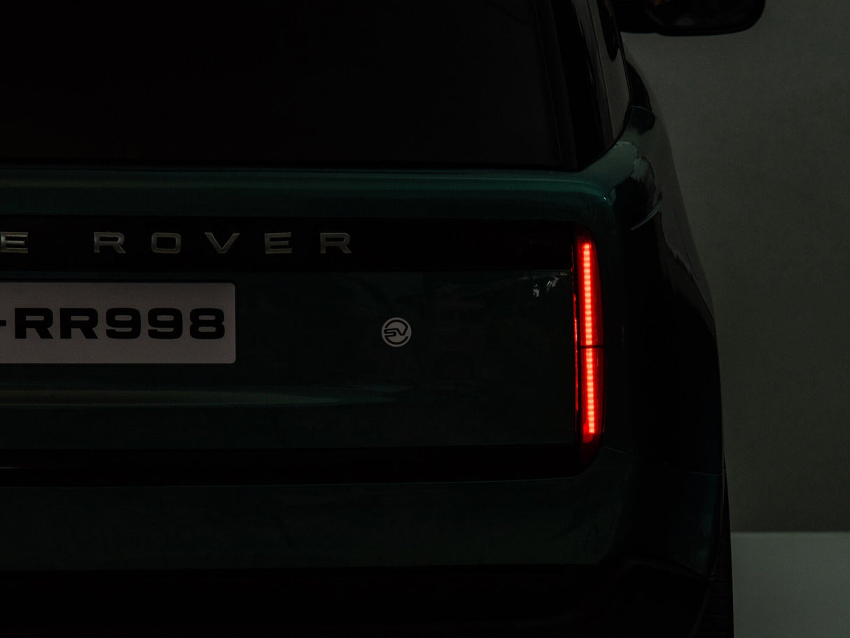 The image showcases the rear section of a dark green kids ride-on Range Rover, highlighting its sleek tail light and left rear end. The license plate reads LR-RR998, and a round badge is visible, resembling the Black 24V Kids Range Rover with premium features and parental control.