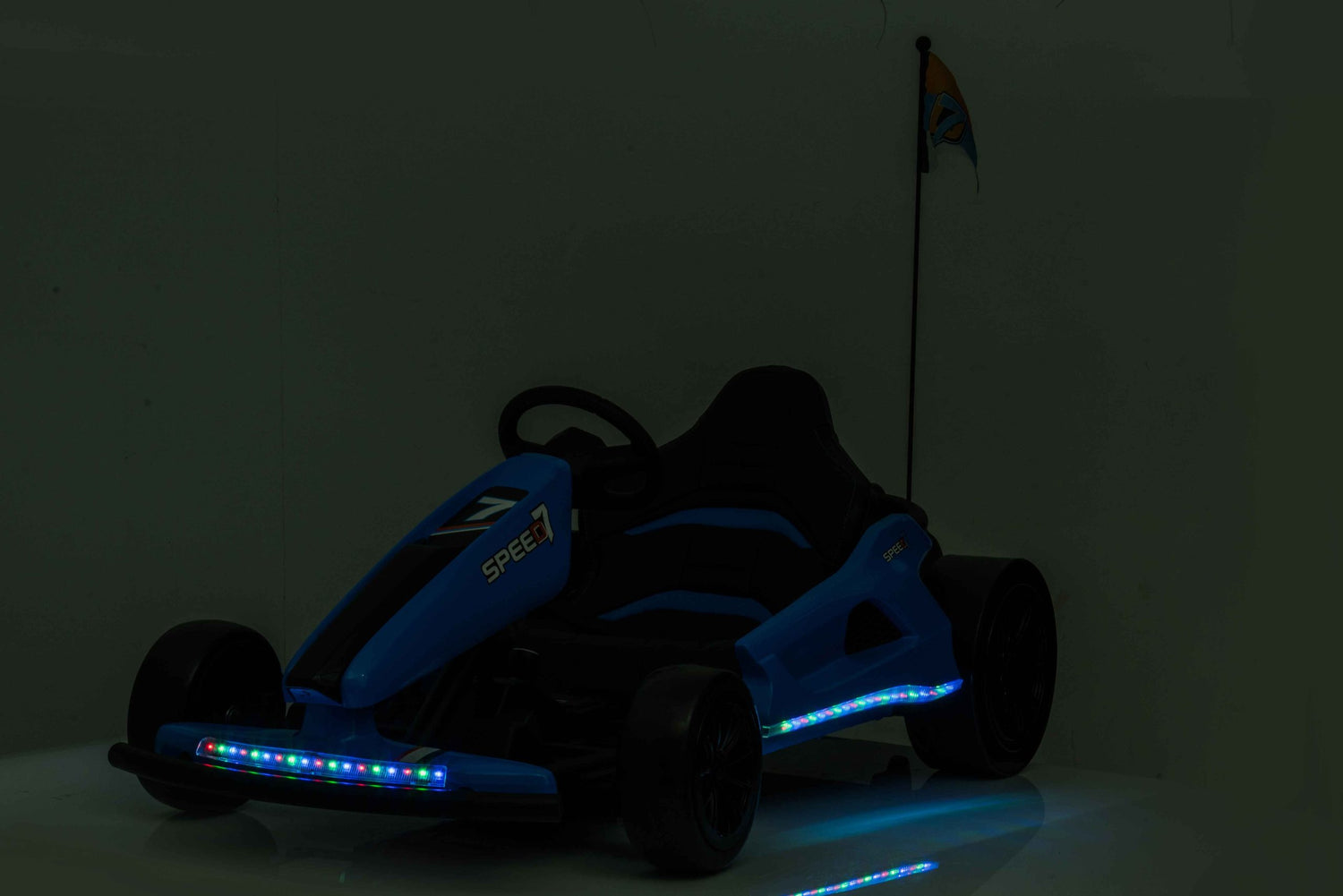 A Grey Big Kids 24V Ultra-Violent Complete Edition Drifting Go-Kart is parked indoors, featuring LED lights and a small rear flag. Its vibrant glow stands out against the dark background.