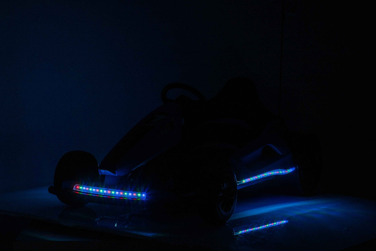 A silhouetted Pink 24V Ultra-Violent Big Kids Complete Edition Drifting Go-Kart with LED lights illuminates wheels and frame in a dim setting, perfect for high-speed drifting adventures.