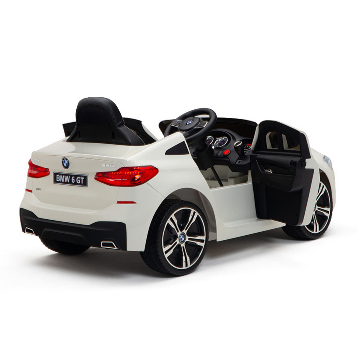 The White 12V BMW GT Kids Licensed 1 Seater Ride On Car features a rear angle view with an open drivers door showcasing the steering wheel and dashboard, sleek black interior, a BMW 6 GT license plate, and stylish black and silver rubber wheels.
