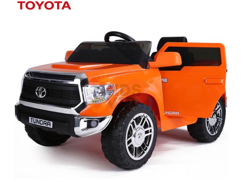 The Orange 12V Licensed Toyota Tundra Kids Ride On Truck features a 12V battery, large detailed wheels, a black steering wheel, an open drivers door, and the Toyota logo above the windshield.