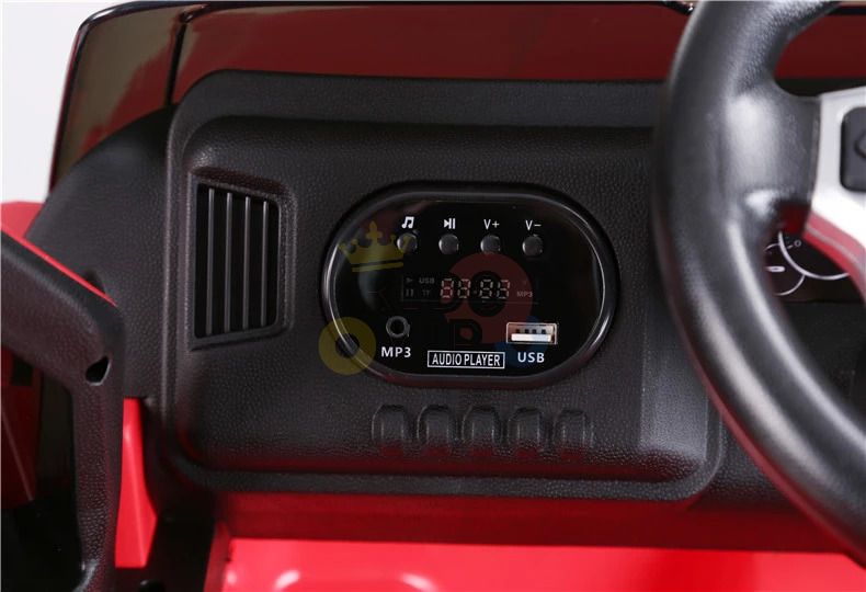 Close-up of a dashboard in the Red 12V Licensed Upgraded Toyota Tundra Kids Ride On Truck, featuring a black panel with music playback buttons and MP3/USB ports. The steering wheel is partially visible on the right, complementing the sleek black and red interior.