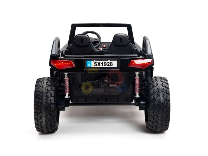 A toy electric car viewed from the rear showcases black seats, oversized rubber wheels, and red suspension springs. Eye-catching backlights and a steering wheel hint at adventure. The license plate SX1928 marks it as the Pink 24V/4X4 Dune Buggy Ride On UTV with Rubber Wheels and RC.