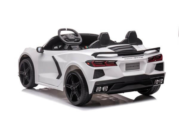 A white toy car, similar to the Kids Premium 24V White Corvette C8 Dual-Seater, boasts leather seats and EVA wheels. It features a visible steering wheel, side mirrors, detailed rear lights, and a spoiler with Corvette boldly emblazoned on the back for authenticity.