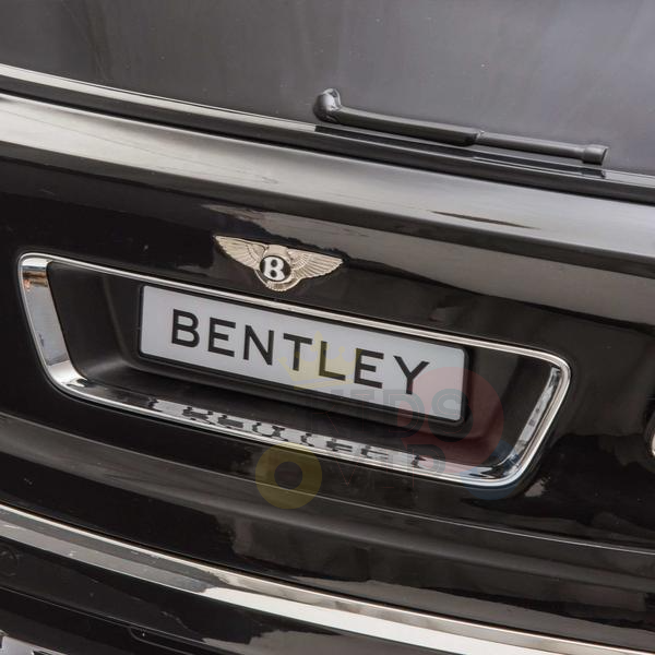 Close-up of the Black Licensed Bentley Bentayaga Complete Edition 12V Kids Ride On Car, showcasing the BENTLEY logo license plate. Chrome accents and the iconic winged emblem elevate its luxury look, while plush leather seats inside ensure comfort.