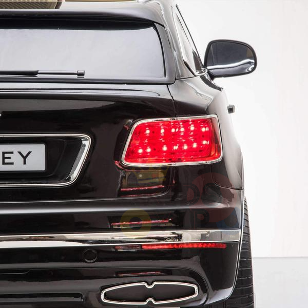 Close-up of a Black Licensed Bentley Bentayaga Kids Ride On Car, showcasing sleek design, distinctive red taillights, chrome accents, and a visible brand logo. The well-lit scene highlights the cars glossy finish and luxurious features.