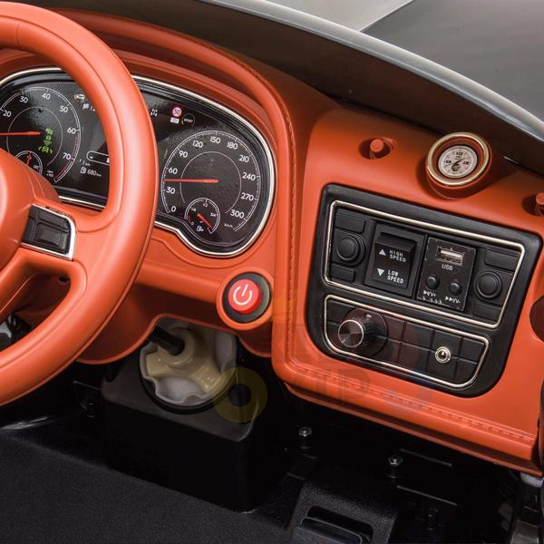 Close-up of an orange dashboard showcasing a steering wheel, speedometer, and control panel with buttons and a USB port. The sporty design combines digital and analog elements, complemented by luxurious leather seats like those in the Black Licensed Bentley Bentayga 12V Kids Ride On Car With RC.