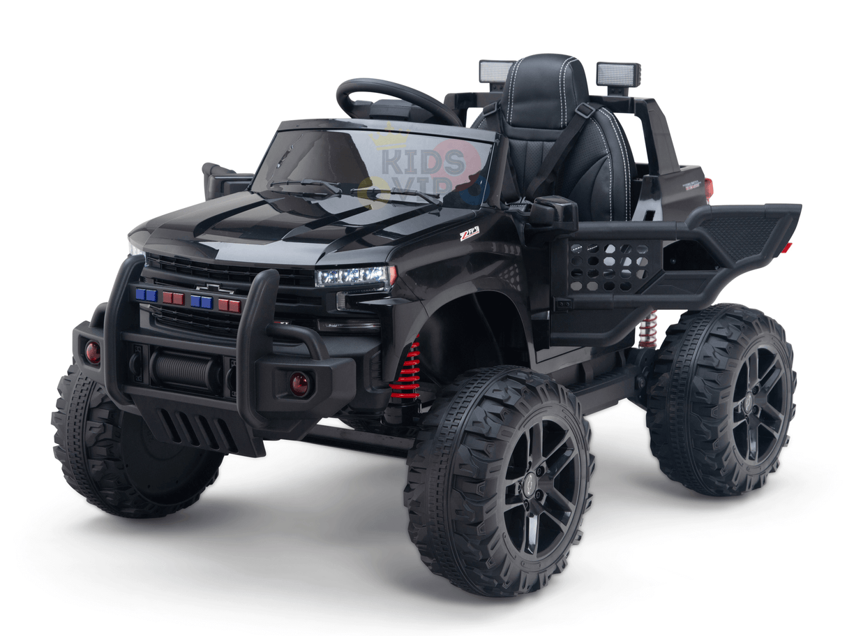 A mini black toy truck, powered by a 24V battery, resembles a lifted Chevrolet Silverado with oversized tires, colorful sticker lights on the grille, side mirrors, and detailed design for kids to ride.