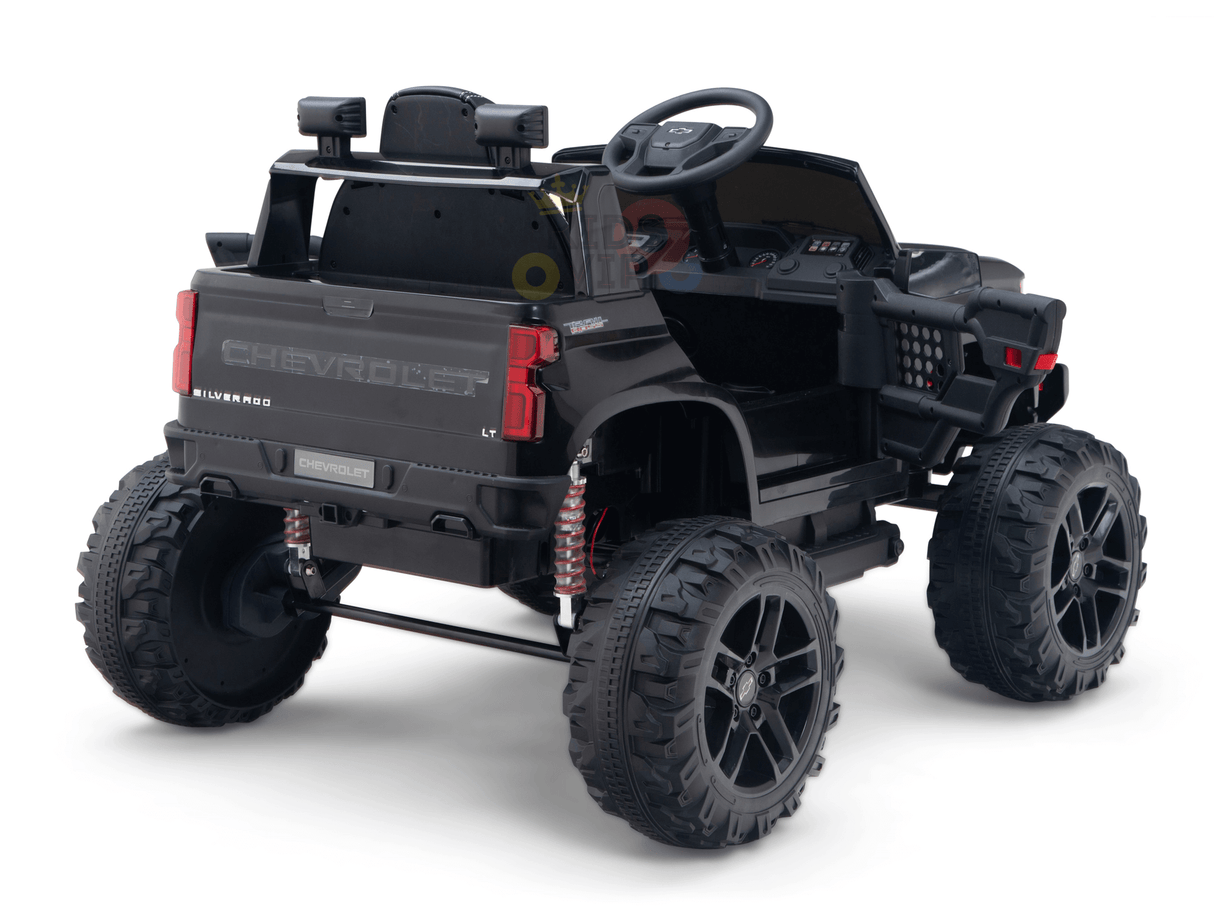 A Black Official 24V Chevrolet Silverado Lifted Kids Ride-on Truck features large off-road wheels, a detailed interior, visible rear branding, and is showcased at an angle highlighting the back and side.