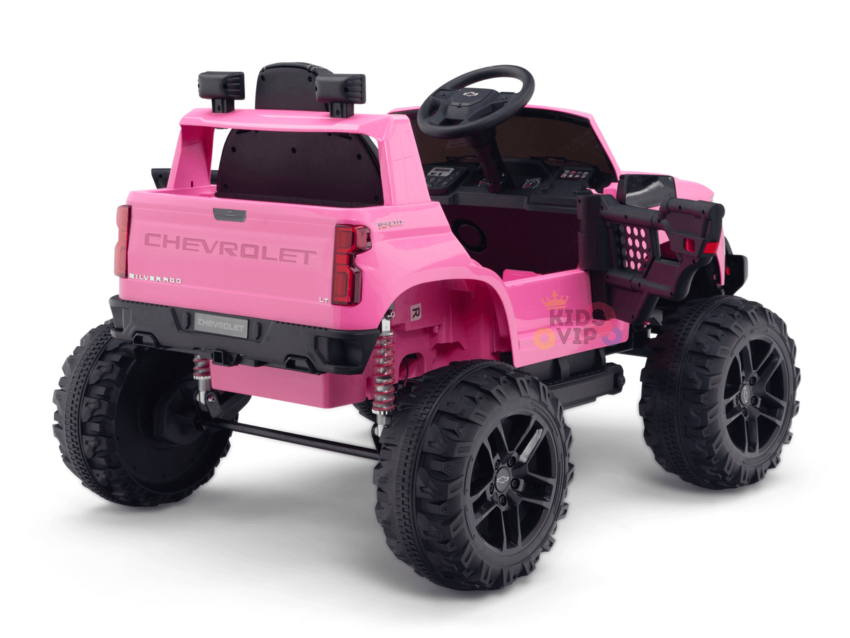 The Pink 24V Chevrolet Silverado Kids Licensed 1 Seater Ride On Lifted Truck features large black rugged wheels, realistic detailing, and an open cabin. It includes a steering wheel, grill guard, and authentic brand markings on the back and sides.
