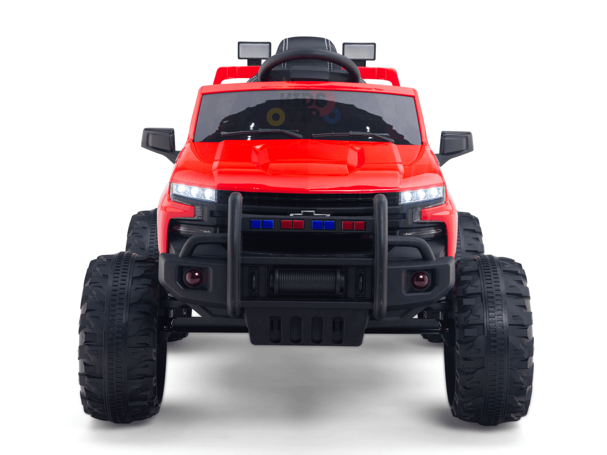 The Red 24V Chevrolet Silverado Kids Licensed 1 Seater Ride On Truck features oversized black tires and a rugged front bumper, designed for off-road play. Its visible headlights and side mirrors enhance its playful yet durable look.