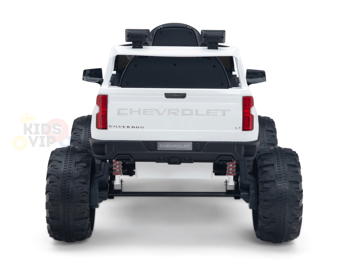 A rear view of the White 24V Chevrolet Silverado Kids Licensed 1 Seater Ride On Lifted Truck with oversized off-road wheels and suspension is displayed on a white background, partially showing the Kids VIP logo on the left.
