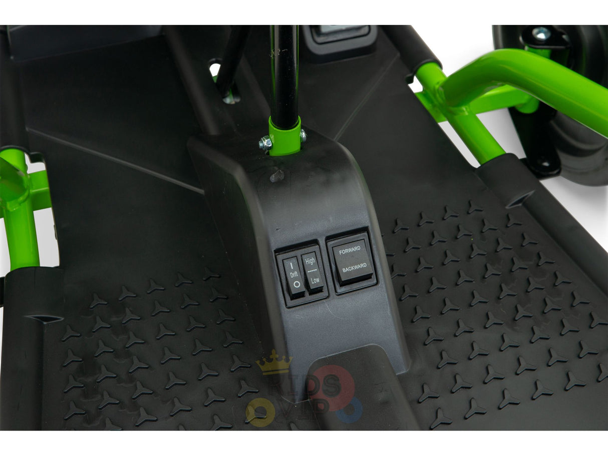 Close-up of the Green 24v Sport Challengers footwell in black and green, featuring Forward and Backward switches. The textured floor with arrow-like patterns enhances grip, ideal for exciting outdoor drifting adventures.