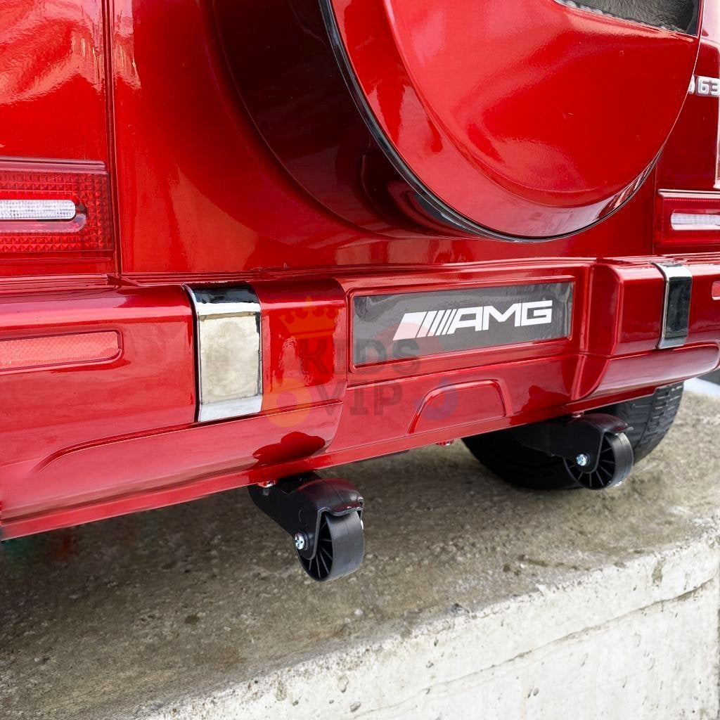 The rear of the red 2 Seats 4x4 Official Mercedes Benz G63 Complete Edition Kids Ride On Car displays a spare tire cover and AMG branding. The bumper has two small wheels underneath, all powered by a 24V battery, sitting on a concrete surface.