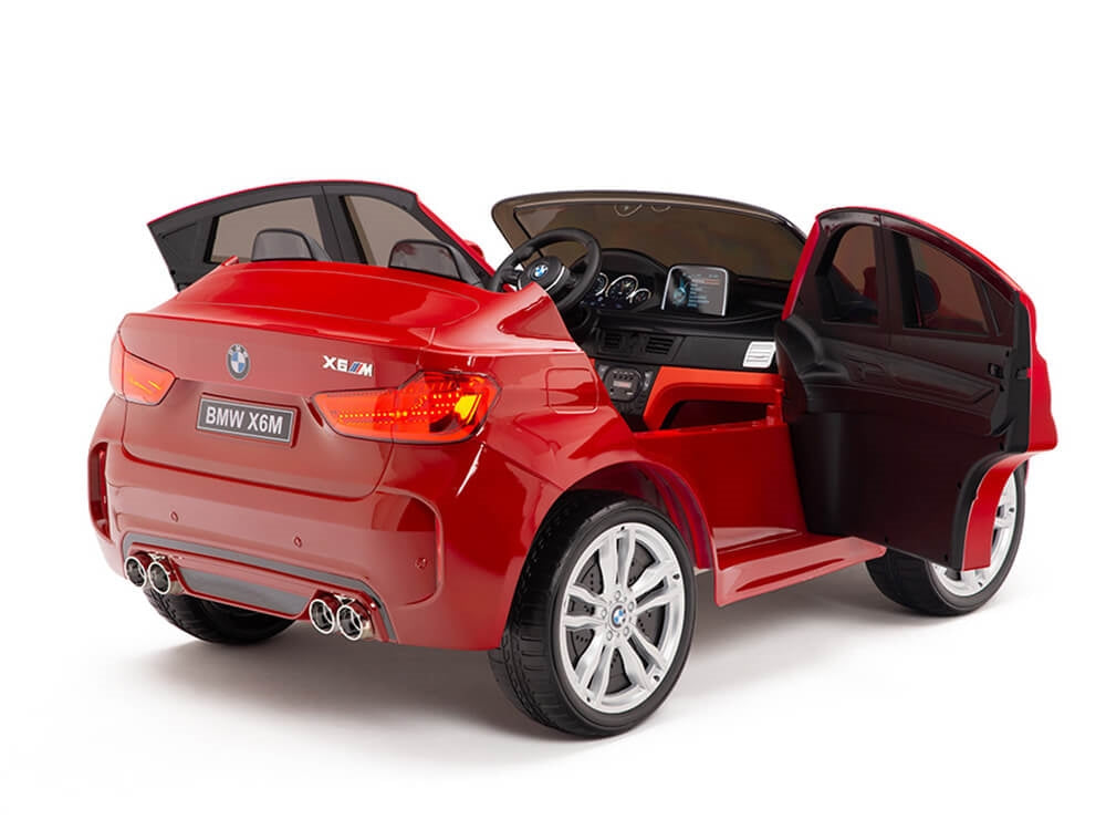 The Red 12V Licensed XXL BMW X6 Ride On Car With Remote Control features a detailed interior, openable doors, silver wheels, and a mini steering wheel. It mimics the real X6M with realistic buttons and displays, offering kids an exciting driving experience.
