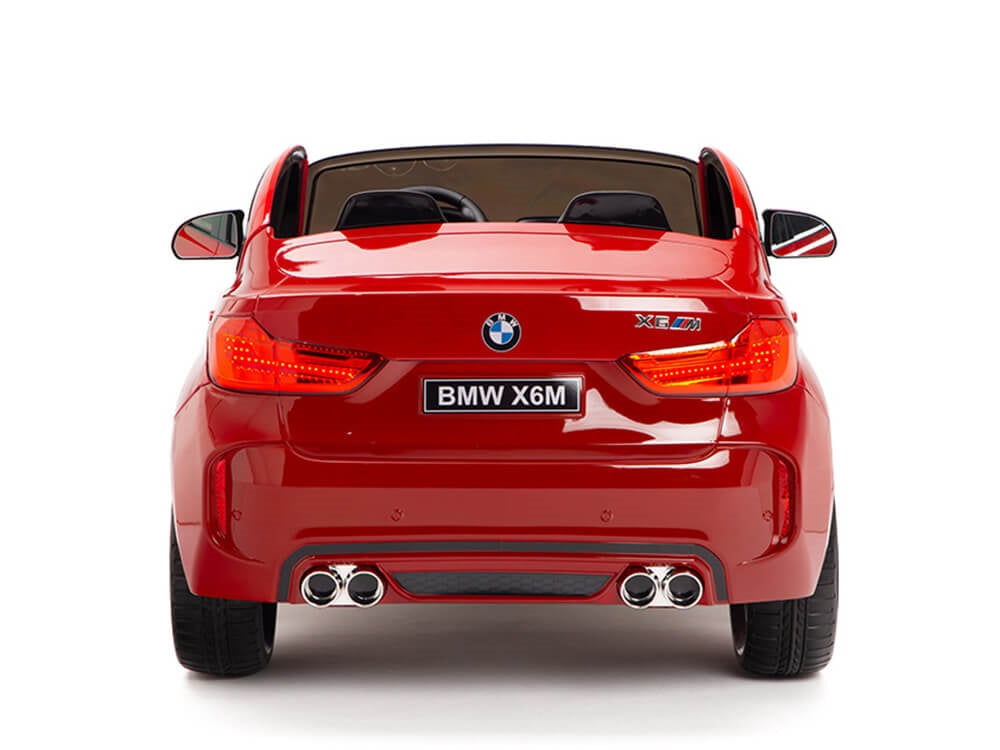 A rear view of the Red 12V Licensed XXL BMW X6 Ride On Car showcases its detailed exterior, including taillights, exhausts, and BMW logo. The license plate reads BMW X6M, with a convertible top down to reveal the interior seats for immersive fun.