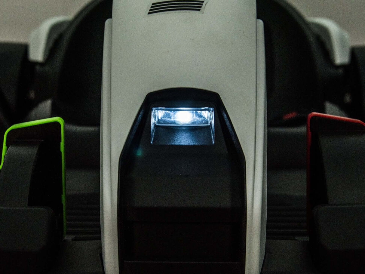 Close-up of a futuristic, sleek component from the Big Kids Powerful 24V Speedster Drifting Go-Kart, featuring a glowing blue light in the center and contrasting green and red elements on each side. Its high-tech design suggests efficient operation powered by 24V HP motors.