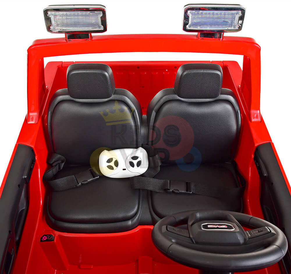The Red 2x12V Licensed 4WD GMC Sierra Kids Ride On Car with RC features a sleek black two-seater interior, a gaming wheel on the left seat, an actual steering wheel, and two decorative overhead lights for flair.