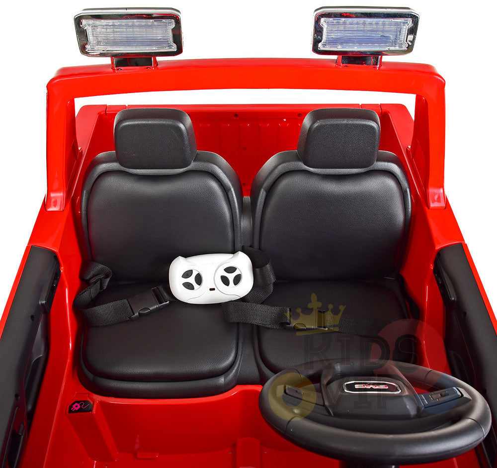 The interior of the Pink 2x12V Licensed 4WD GMC Sierra Kids Ride On Car with RC features two black seats. A child-sized seatbelt secures a white teddy bear face-shaped cushion, and two rectangular overhead lights enhance the vibrant electric car experience for kids.