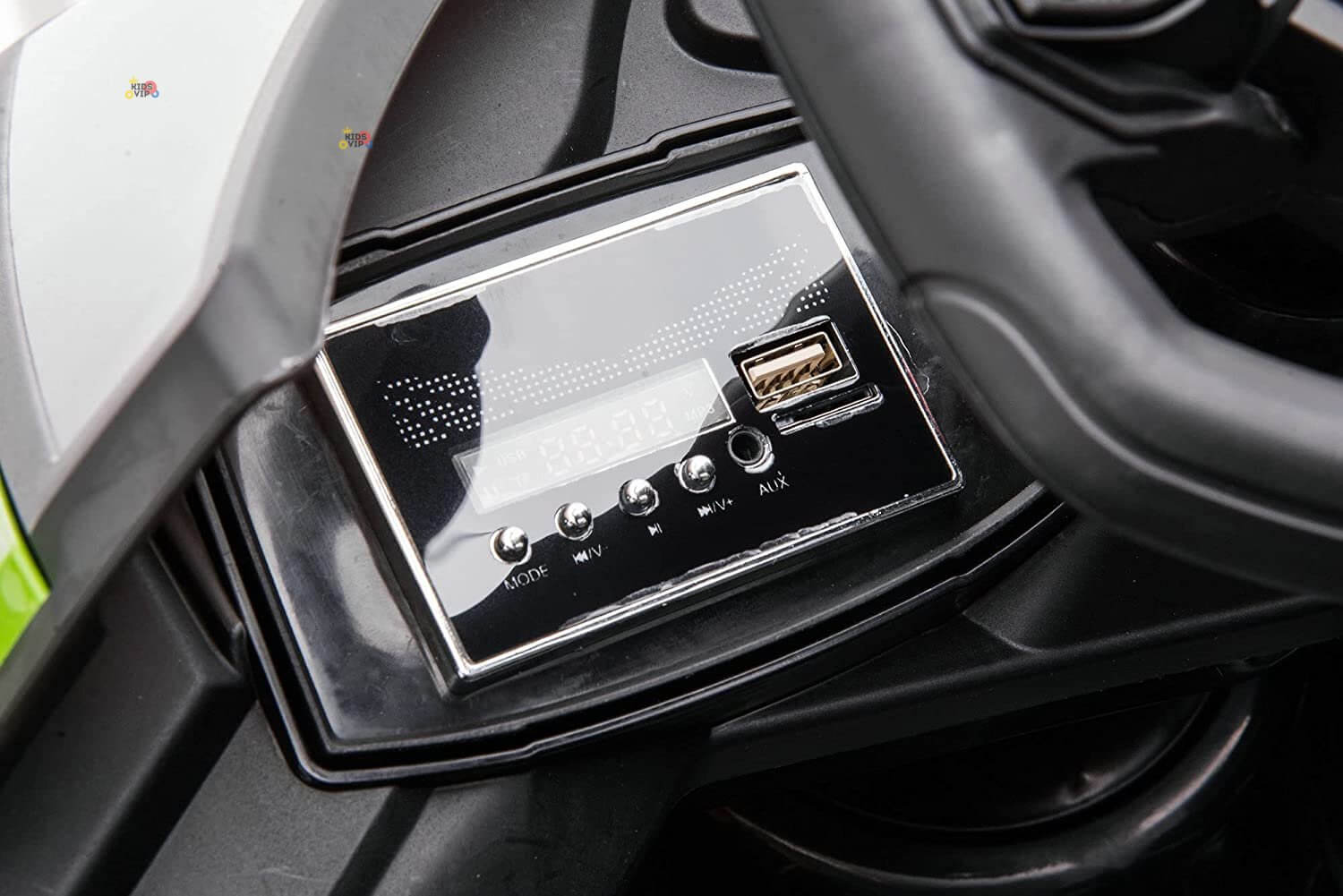 Close-up of the Green 12V Official Lamborghini Vision GT Kids Ride-on Car dashboard, showcasing a sleek black stereo system with buttons for MODE, VOL⁺, VOL⁻, and AUX, plus a USB port and digital display, inspired by the Lamborghini Vision GT.
