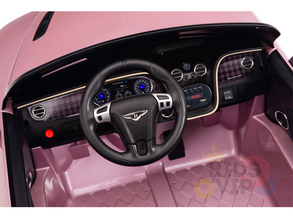 A peek inside the pink Bentley GTC 12V Ride Ons dashboard reveals a black steering wheel, illuminated control panel, and diamond-patterned trim. This licensed Sport Edition includes a red power button and blue-lit gauges for parental remote control safety.