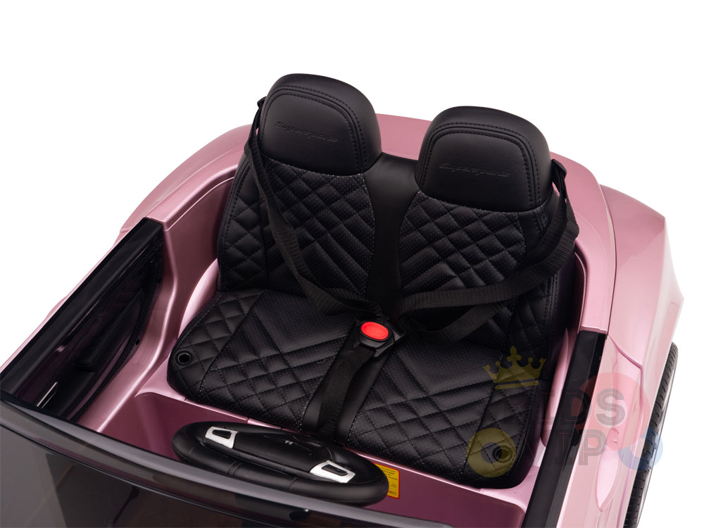 The Pink 12V Bentley GTC Kids Licensed Ride On Car boasts black quilted leather seats with harness-style seat belts, a sleek interior, and a sporty design inspired by the Bentley Continental Sport Edition. It features visible stitching details and a black steering wheel.