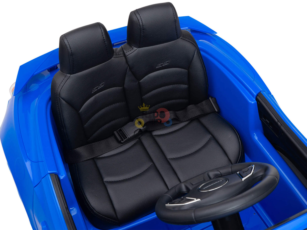 The Blue Official Sport 12V Chevrolet Camaro Kids and Toddlers Ride on Car features a detailed interior with two black leather-look seats, intricate stitching, embossed designs, and a black seatbelt. The dashboard and steering wheel are prominently visible for little drivers.
