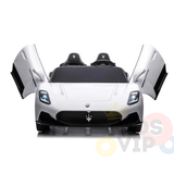 This premium white XXL 24V Maserati MC20 toy car boasts butterfly doors, black accents, and lit headlights. Its sleek design features plush leather seats, showcased from the front against a pristine white background.