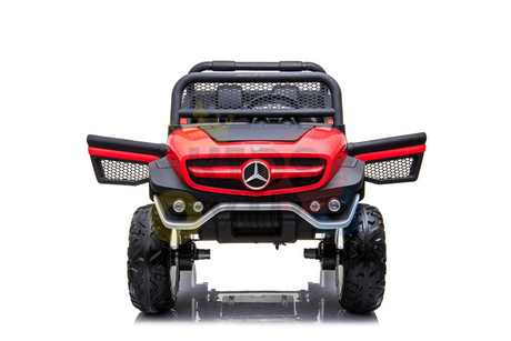 The Red 12V/4X4 Mercedes Unimog Junior Ride On UTV features a remote control, rugged off-road design, red and black color scheme, large tires, and a distinctive grille with circular emblem. Its robust frame boasts intricate mesh details for an authentic look.
