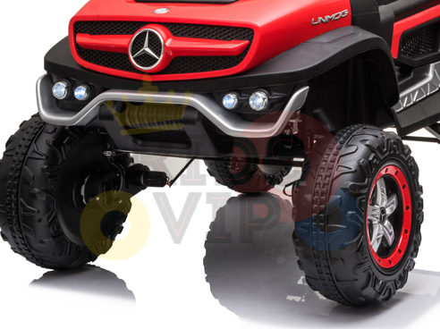 Close-up of a Red 12V/4X4 Official Mercedes Unimog Junior Ride On UTV with remote control, resembling an off-road truck. It features oversized black and red wheels, a silver grille, and a prominent front logo. The vehicle is mainly red with black accents.