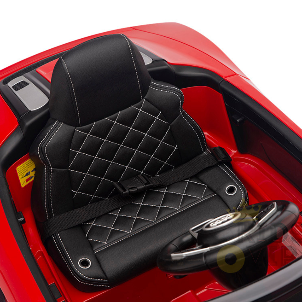 The Red 12V Audi R8 Licensed 1-Seater Ride On Car features a black leather car seat with white diamond stitching and a seatbelt. Its steering wheel sits against a red interior, and it includes upgraded EVA rubber wheels for an enhanced ride.