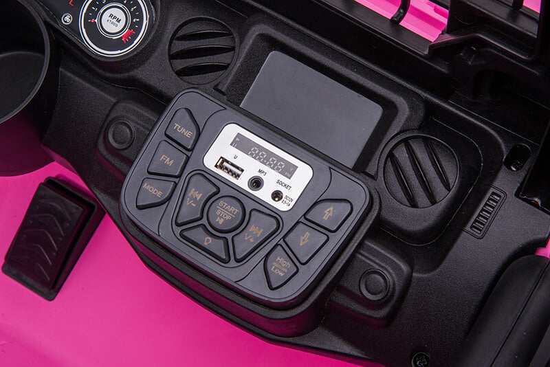 Close-up of a pink dashboard in the Pink 24V/2WD Xtreme Edition Ride on Truck, showcasing a control panel with mode, music, volume buttons, USB port, and digital display reading TOTAL: 00:00. A glimpse of the cup holder and foot pedal complements this adventurous 2-seater toy.