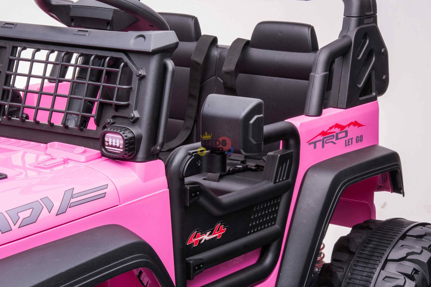 Close-up of the Pink 24V/4WD Xtreme Ride on Truck featuring black leather seats, a grid-like windshield, side mirror, TRD and 4x4 logos in black and red, rugged Eva wheels for tough terrain, and a parental remote control for safety.