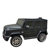 The Limited 12V Matte Edition Mercedes Benz AMG G63 Kids and Toddlers Ride-On Truck, RC, is a sleek black replica SUV with silver rims, side mirrors, and a hood ornament, offering upgraded technology to mimic a luxurious miniature vehicle.