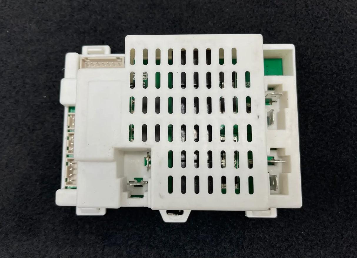 The 24V McLaren Go Kart Receiver, a white plastic electronic component with slots and connectors, sits on a dark background. Its cover, with rectangular ventilation holes, reveals inner circuits. This item is part of our Final Sale and is non-refundable.