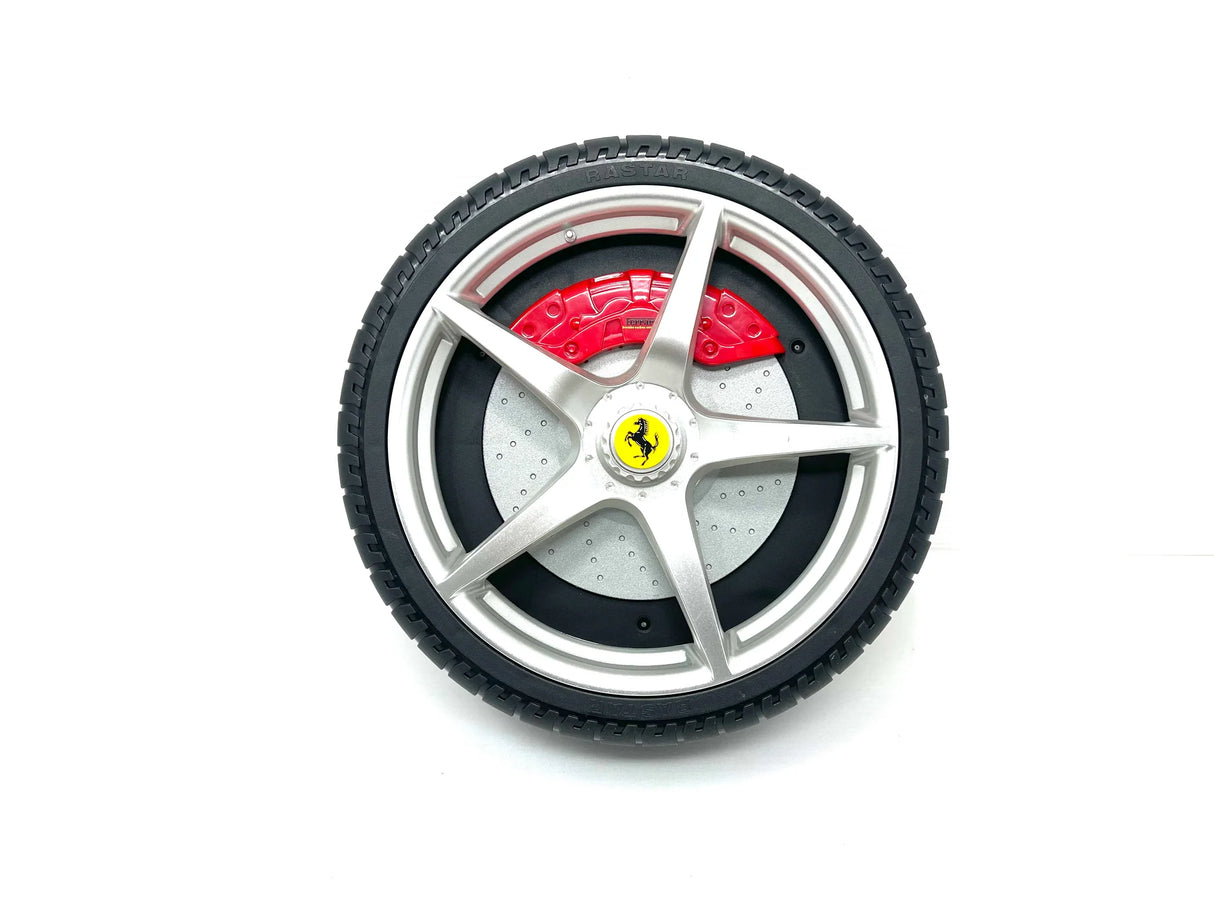 The 12V LaFerrari Wheel features a silver alloy rim with five spokes and a central yellow logo on black. A red brake caliper peeks through the treaded tire pattern, all set against a white background, making it an ideal replacement part.